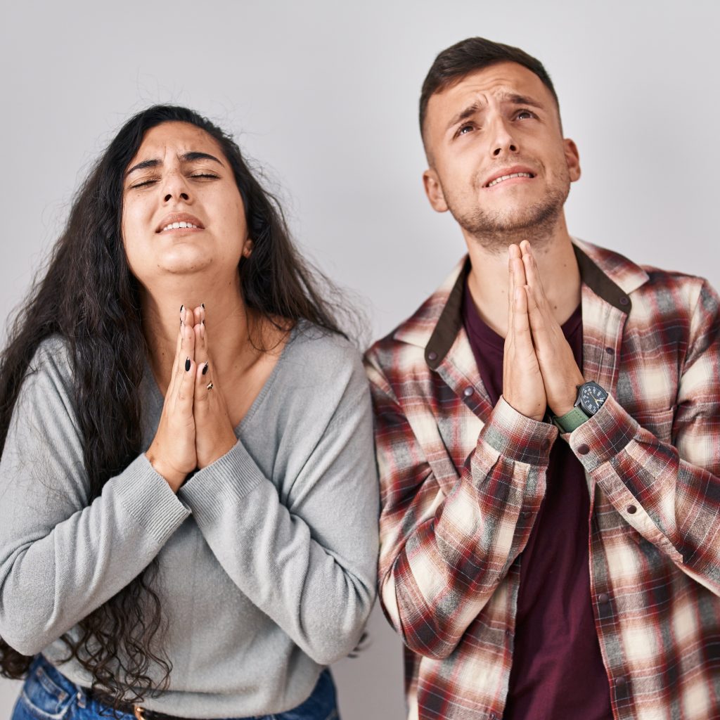 Young Hispanic Couple Standing Over White Background Begging And Praying With Hands Together With Hope Expression On Face Very Emotional And Worried. Begging.