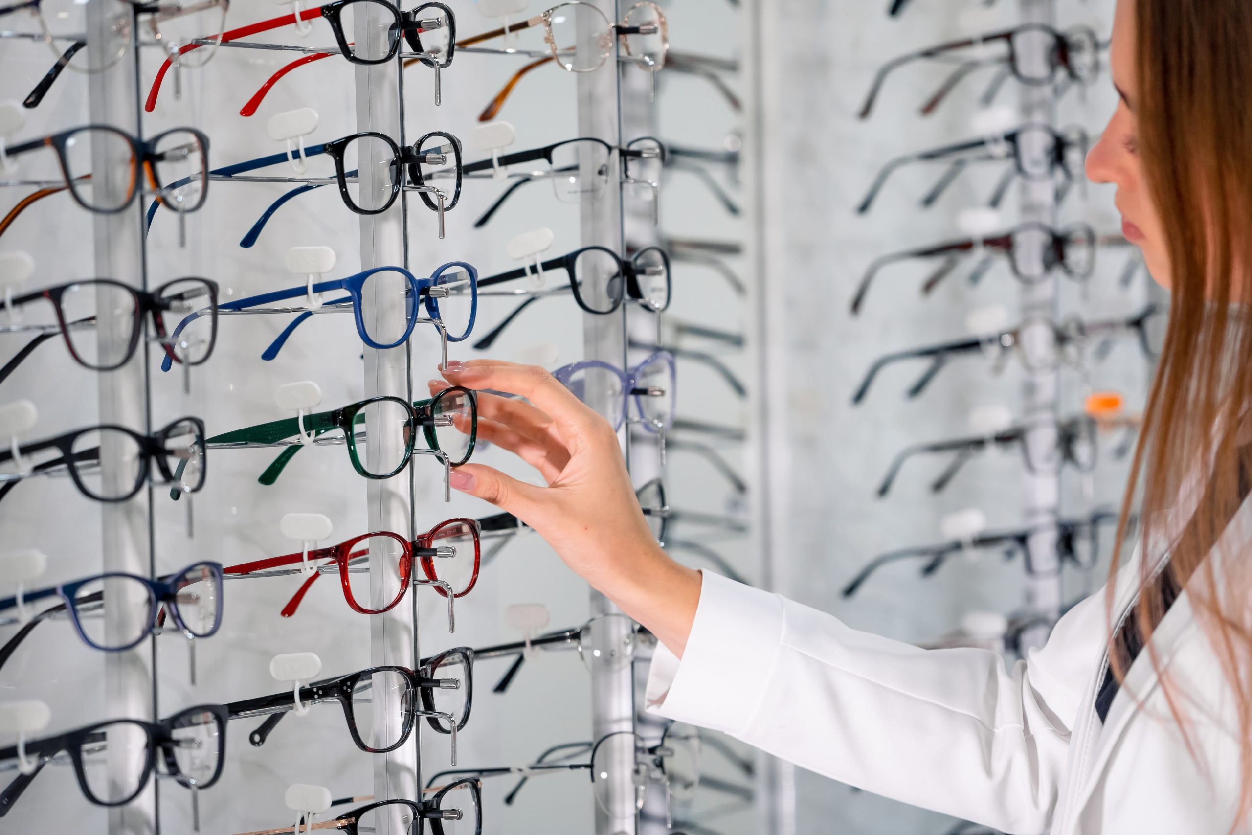Showcase With Spectacles In Modern Ophthalmic Store. Woman Hands With Glasses. Closeup.